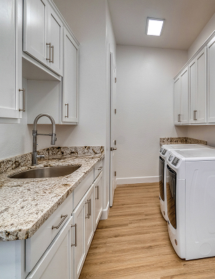 laundry room with marbel countertops and white cabinets